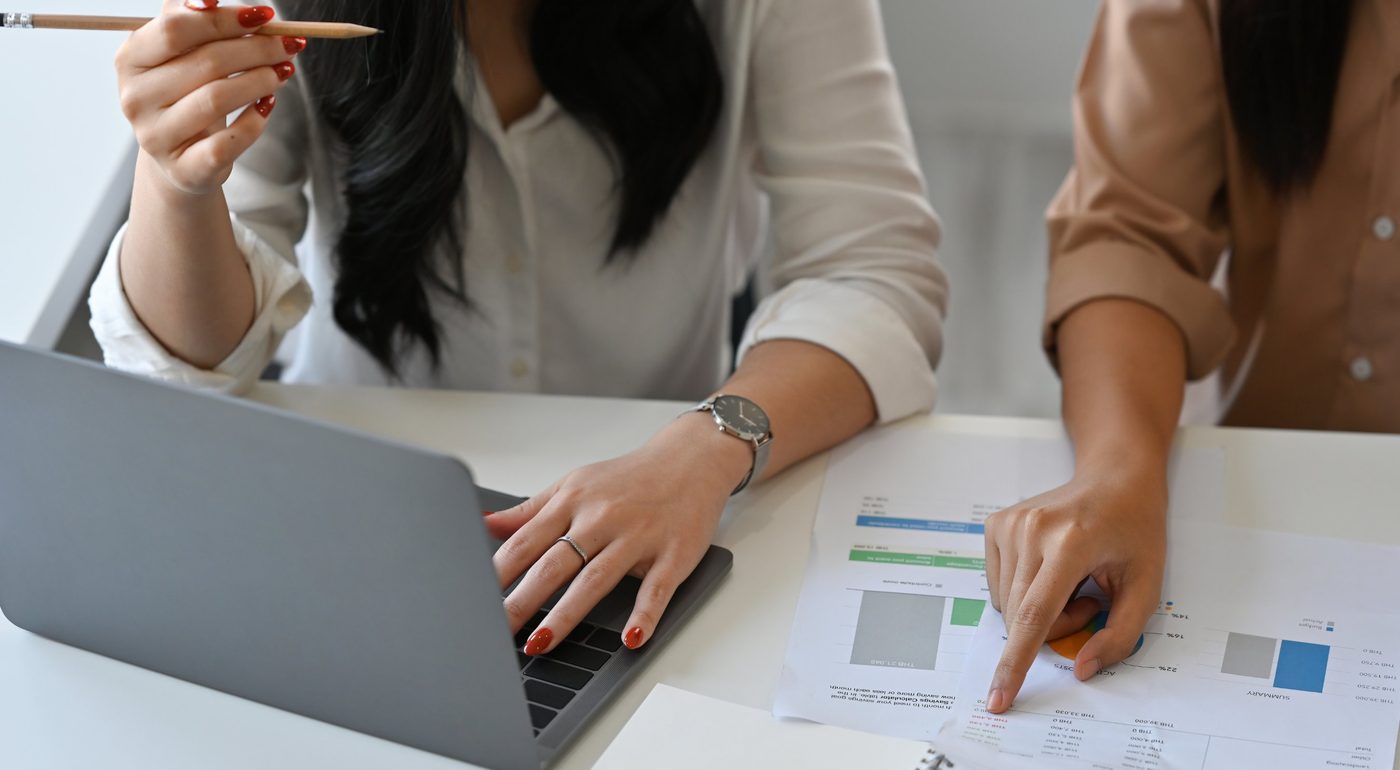 Two people reviewing performance charts together beside a laptop