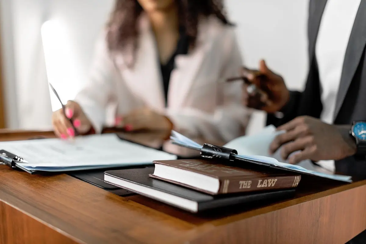 Legal professionals reviewing paperwork beside law books at a desk